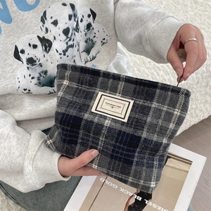 Macro view of vintage plaid wool cosmetic bag showing the zipper and brand tag detail