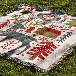 Detail of woven Christmas blanket showing reindeer, trees and tassels on green grass
