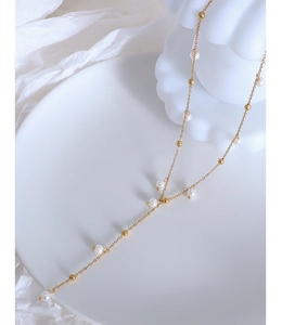 Detail of Y-shaped 18k gold-plated titanium necklace with faux pearls on white silk