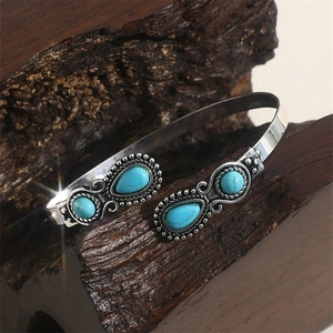 Vintage silver alloy open bangle featuring turquoise stones on a dark wood background