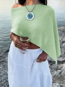 Detail of green textured sheer beach cover-up top against a coastal rock background