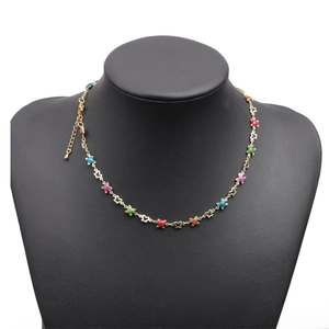Gold necklace with colorful star charms on a black mannequin display against white background