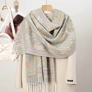 Detailed view of paisley core-spun yarn scarf with tassels on beige coat