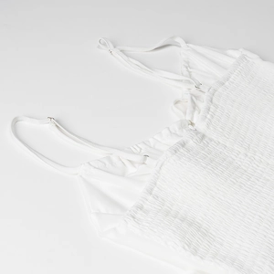 Détail de robe blanche avec corsage élastique froncé et fines bretelles réglables