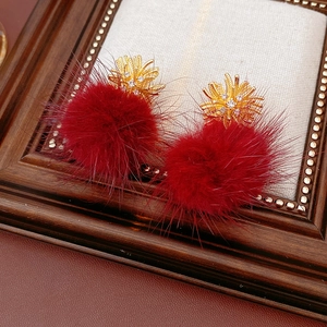 Detailed macro view of festive red fur pom-pom earrings with gold rhinestone fireworks