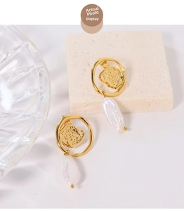 Detailed view of baroque pearl earrings with irregular gold hammered texture on stone