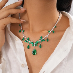 Detail shot of vintage silver-tone necklace with emerald green crystals on a model