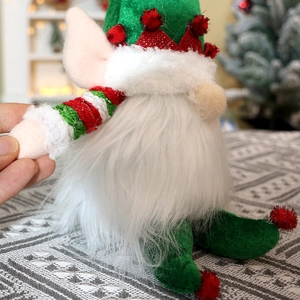 Detail of Christmas gnome plush with green sequined hat and striped arms for decor