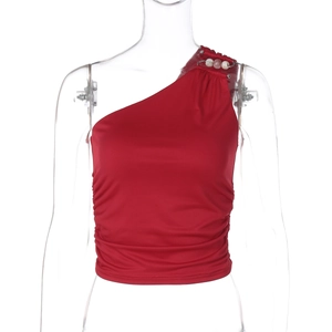 Dettaglio del crop top rosso monospalla con spilli metallici e decorazioni di perline