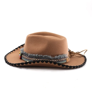 Detail of brown felt cowboy hat featuring ethnic woven band, wood beads and feathers