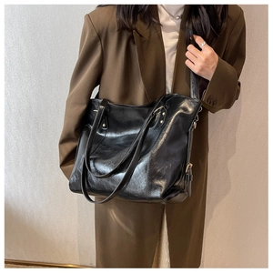 Gros plan d'un grand sac cabas noir en cuir porté par un mannequin en blazer marron