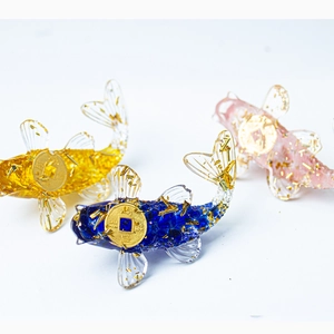 Three crystal koi fish figurines in yellow, blue, and pink with golden coins for decor