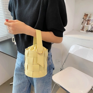 Pale yellow woven bucket bag with leather texture and gold hardware rings for women