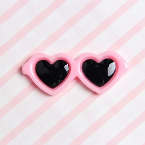 Detailed view of pink heart-shaped pet glasses accessory with black lenses for hair clips