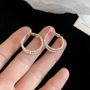 Dettaglio macro di orecchini a cerchio argento con trama a diamante e chiusura a scatto