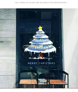 Close-up of blue snow-covered Christmas tree window sticker with Merry Christmas text
