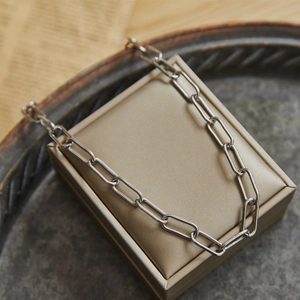 Silver chunky paperclip chain necklace for women displayed on a jewelry box and stone