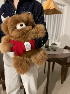 Detalle de guantes de punto rojos en un oso de peluche en un ambiente hogareño acogedor