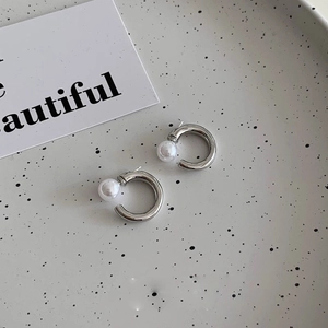 Detail view of silver C-shaped hoop earrings featuring a polished finish and white pearl