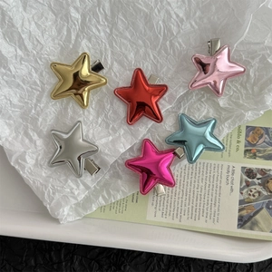 Close-up of colorful star hair clips in gold, red, and pink on magazine background