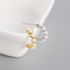 Macro shot of gold and silver S925 C-shaped hoop earrings with inlaid pearls