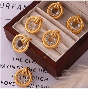Macro detail of gold circle earrings with clear zircon stones in a wooden jewelry box