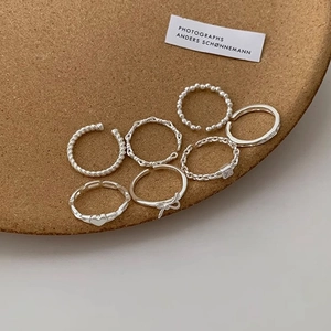 Detailed view of a 7-piece silver twist and heart ring set on a cork surface