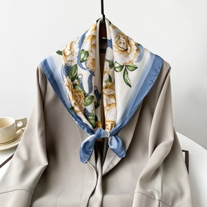 Detailed shot of yellow floral satin silk scarf tied on a chic beige blazer lapel