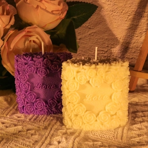 Macro detail of rose flower column candles with embossed Love text and 3D floral textures