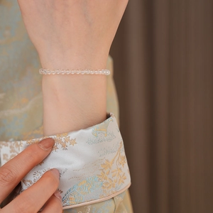 Close-up of minimalist clear crystal beaded bracelet on wrist with elegant silk sleeve