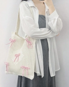 Detailed view of white hollow knit tote bag featuring cute pink bow accents