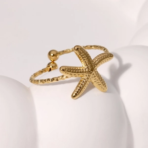 Minimalist gold starfish open ring with polished metal finish on artistic white background
