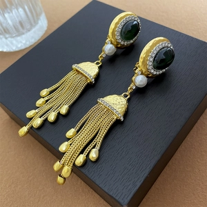 Détails de boucles vintage dorées avec pierre verte, cristaux et longues franges