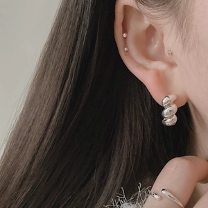 Close-up of tiered sterling silver hoop earrings with spiral texture on female ear