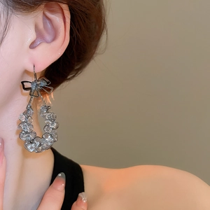 Details von Model mit schwarzen Schleifenohrringen und Perlen-Kreisanhängern