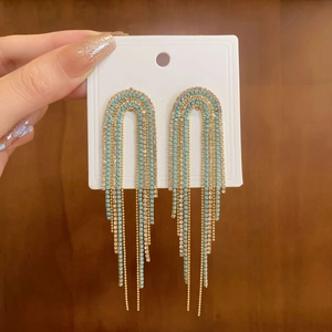 Detail of gold fringe earrings with turquoise beads and sparkling white rhinestones