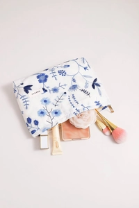 Gros plan d'une trousse à maquillage en toile blanche avec broderie florale bleue et zip