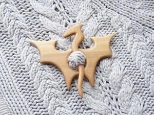 Macro shot of bat-shaped wooden brooch pin on gray knitted sweater texture detail
