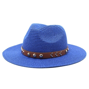 Detail of royal blue straw cowboy hat featuring a brown belt band with metal accents