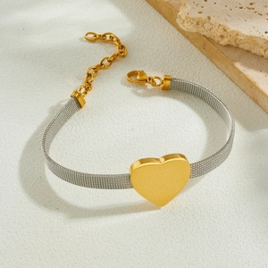 Minimalist gold and silver mesh chain bracelet with heart pendant on stone decor