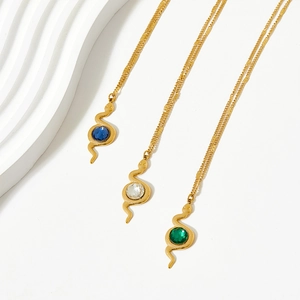 Detailed macro view of snake pendants with green and blue stones on gold necklaces