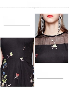 Detail view of the black embroidered dress featuring mesh neckline and floral waist patterns
