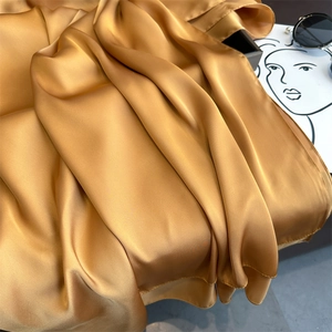 Close-up of elegant gold satin silk scarf showing smooth texture and soft drapes