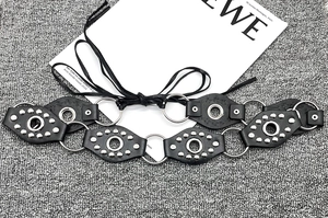 Detail of vintage Y2K black leather belt featuring silver studs and metal ring links