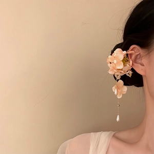 Detail view of a fabric flower hair clip with elegant pearl tassels worn on hair