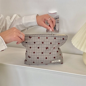 Detailed top view of a polka dot bow cosmetic bag with a zipper on a white desktop