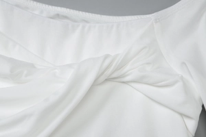 Détail d'une robe blanche à une épaule avec nœud devant et texture en maille côtelée