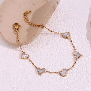 Close-up of 18K gold-plated chain bracelet featuring five white mother-of-pearl hearts