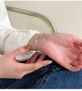 Dettaglio di un bracciale in argento S925 a onde irregolari indossato sul polso femminile