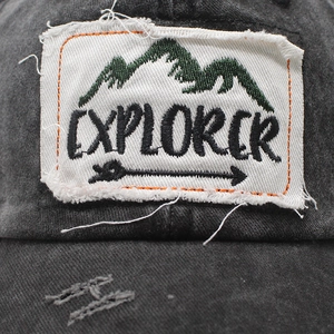 Macro detail of EXPLORER embroidery on distressed washed canvas baseball cap